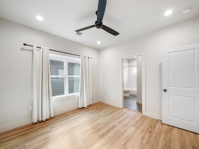 unfurnished bedroom featuring ceiling fan, light hardwood / wood-style flooring, connected bathroom, and multiple windows