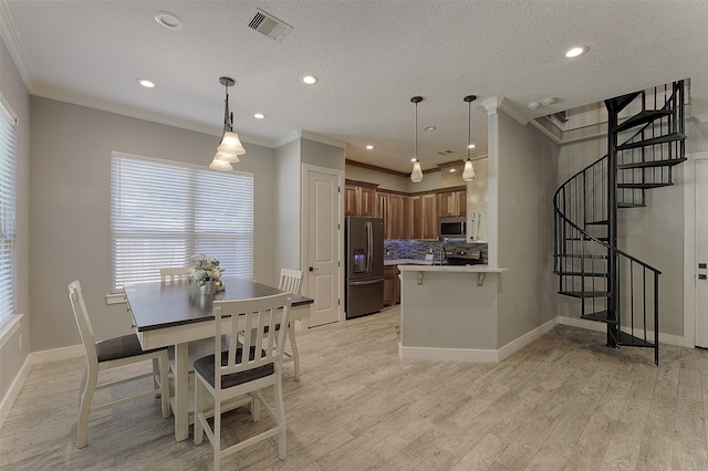 kitchen with appliances with stainless steel finishes, kitchen peninsula, ornamental molding, and light hardwood / wood-style floors