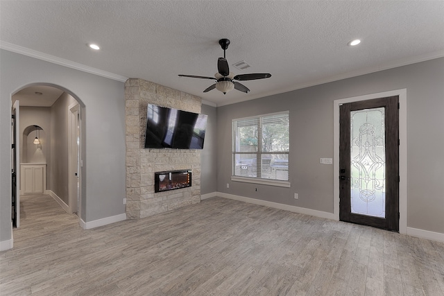 unfurnished living room with a textured ceiling, light hardwood / wood-style floors, a fireplace, crown molding, and ceiling fan