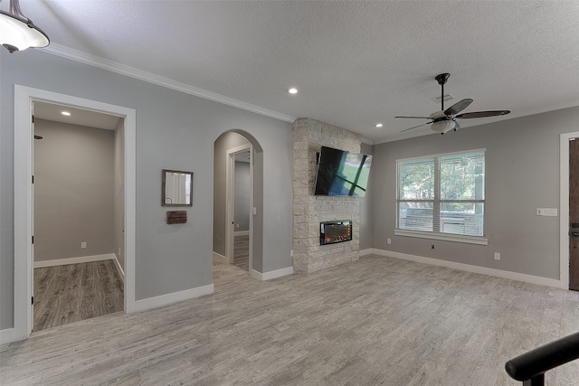 unfurnished living room featuring crown molding, light hardwood / wood-style floors, a fireplace, and ceiling fan