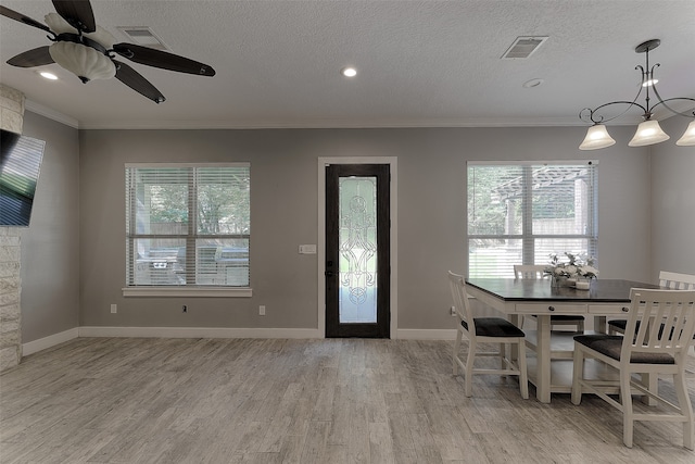 unfurnished dining area featuring a textured ceiling, light hardwood / wood-style floors, a fireplace, crown molding, and ceiling fan