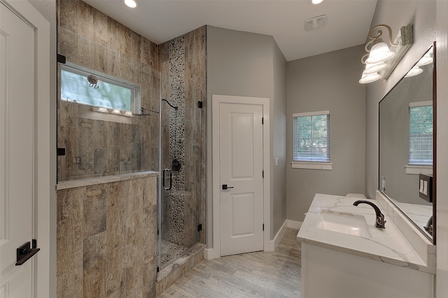 bathroom with wood-type flooring, a shower with shower door, vanity, and plenty of natural light