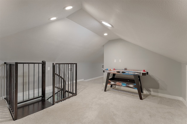 rec room with a textured ceiling, carpet, and vaulted ceiling