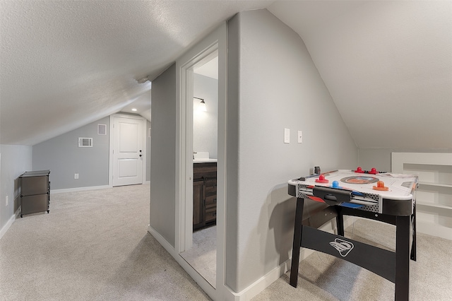 additional living space featuring light carpet, a textured ceiling, and vaulted ceiling