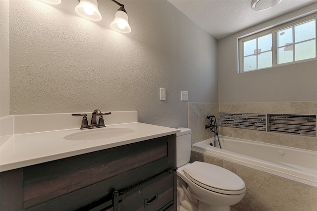 bathroom featuring vanity, tiled bath, toilet, and a textured ceiling