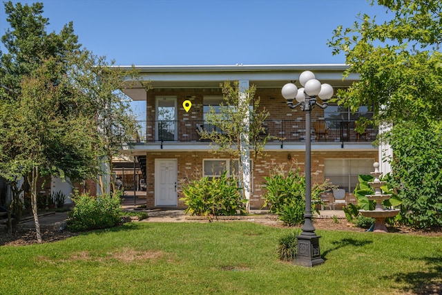 view of front of home featuring a front yard and a balcony