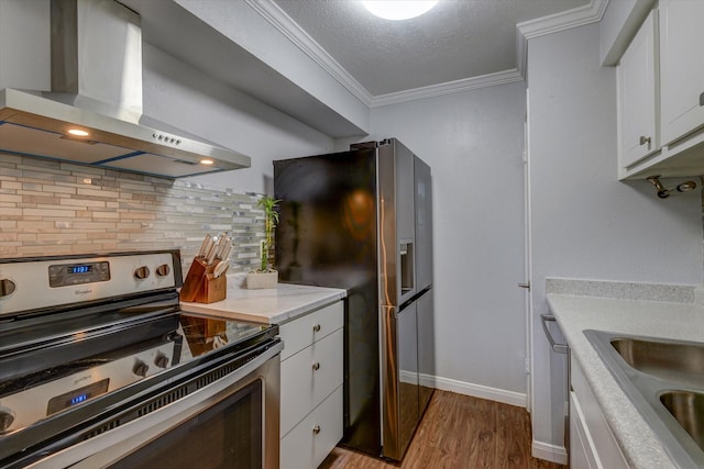 kitchen with wall chimney range hood, decorative backsplash, appliances with stainless steel finishes, light hardwood / wood-style floors, and white cabinetry