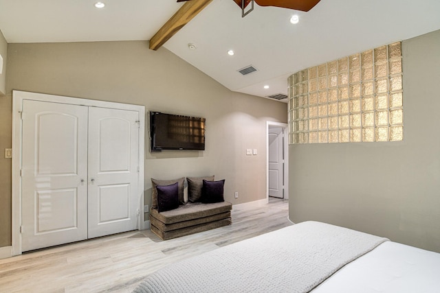 bedroom featuring light hardwood / wood-style floors, a closet, and vaulted ceiling with beams