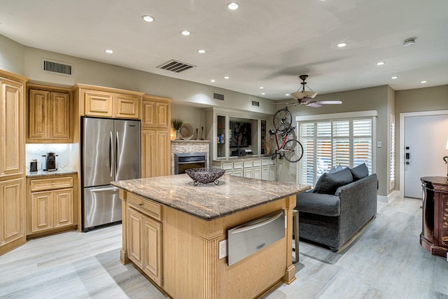 kitchen with a kitchen island, tasteful backsplash, dark stone countertops, stainless steel fridge, and light hardwood / wood-style flooring