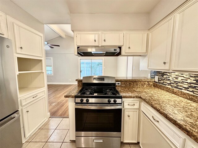 kitchen with dark stone counters, stainless steel appliances, light wood-type flooring, vaulted ceiling with beams, and extractor fan