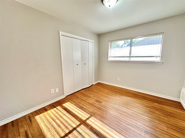 unfurnished bedroom featuring a closet and hardwood / wood-style floors