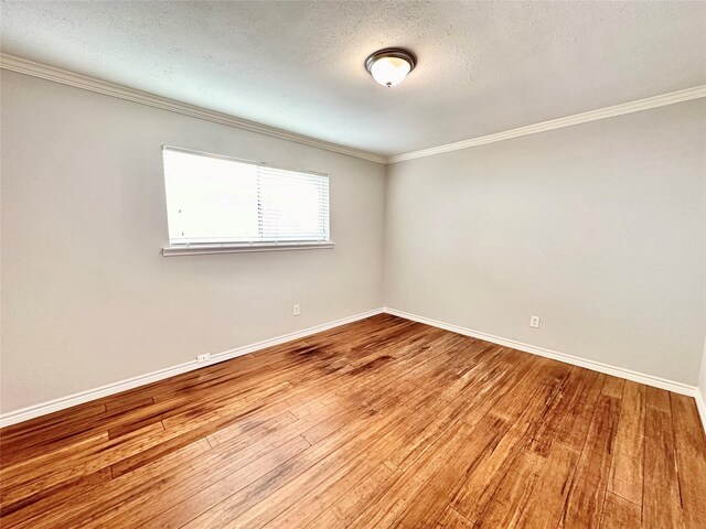 empty room featuring wood-type flooring, a textured ceiling, and crown molding