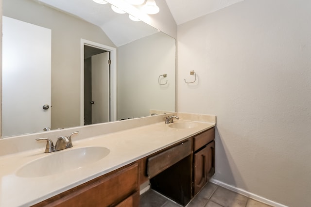 bathroom with tile patterned flooring, vaulted ceiling, and vanity