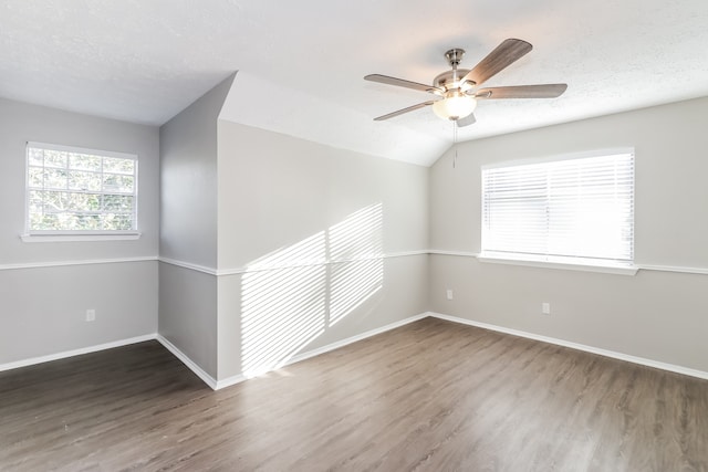 spare room featuring lofted ceiling, ceiling fan, dark wood-type flooring, and a textured ceiling