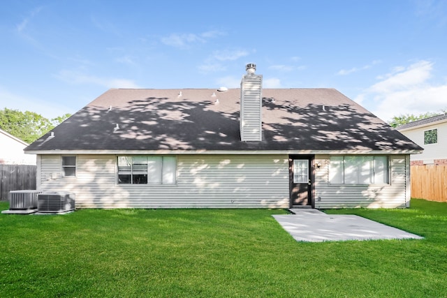 rear view of property featuring a lawn and central air condition unit