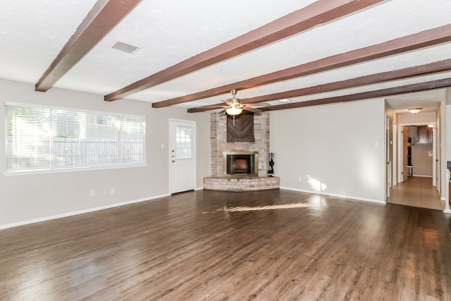 unfurnished living room featuring ceiling fan, beam ceiling, a textured ceiling, dark wood-type flooring, and a fireplace