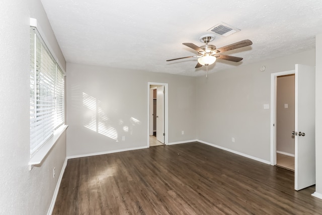 spare room with a textured ceiling, ceiling fan, and dark wood-type flooring