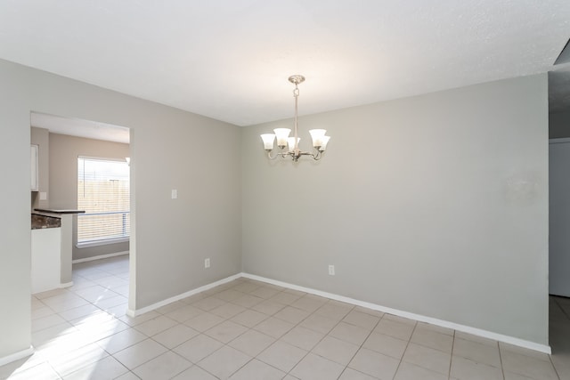 tiled spare room with an inviting chandelier