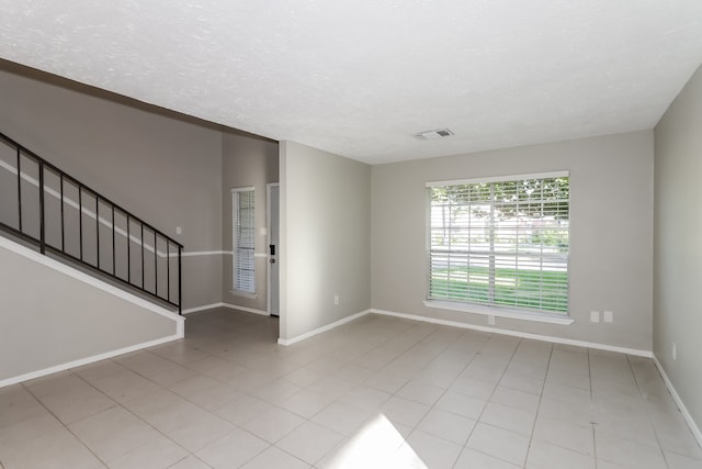 tiled spare room with a textured ceiling