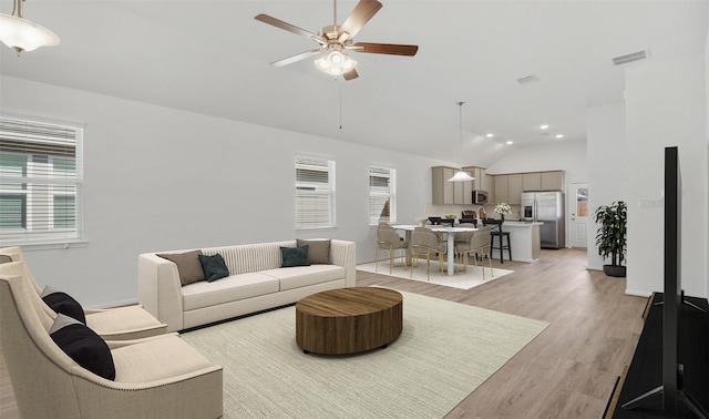 living room with high vaulted ceiling, ceiling fan, and light hardwood / wood-style flooring