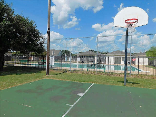 view of sport court with a community pool and a yard