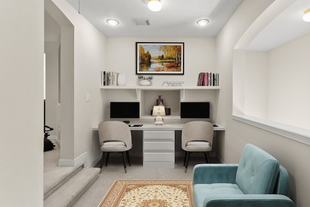 carpeted home office featuring built in desk