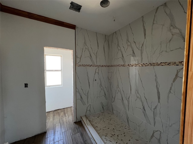 bathroom featuring wood-type flooring and a tile shower