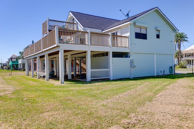 rear view of property featuring roof with shingles, a yard, and a deck