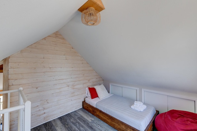 bedroom with wood finished floors, wood walls, and vaulted ceiling