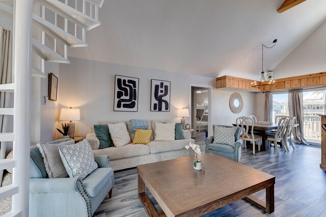 living room with hardwood / wood-style floors, an inviting chandelier, and high vaulted ceiling