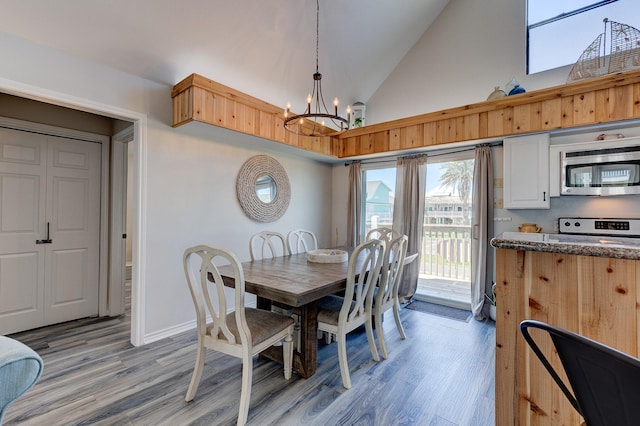 dining room featuring high vaulted ceiling, light wood finished floors, baseboards, and an inviting chandelier