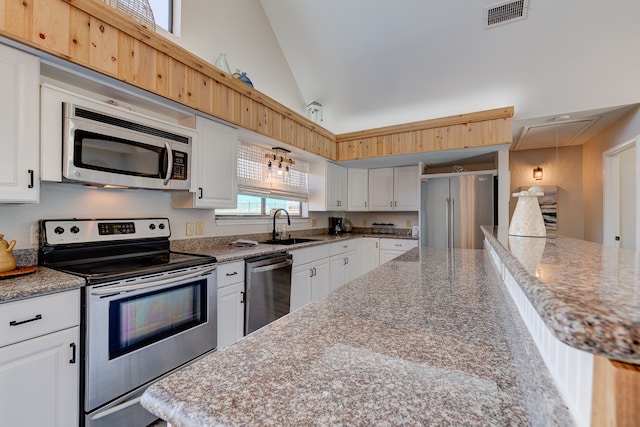 kitchen with a sink, white cabinetry, appliances with stainless steel finishes, and light stone counters