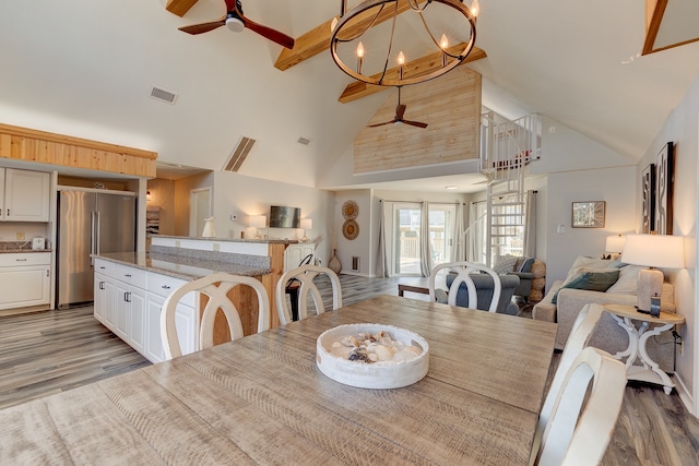 dining area featuring high vaulted ceiling, ceiling fan with notable chandelier, visible vents, light wood-type flooring, and beam ceiling