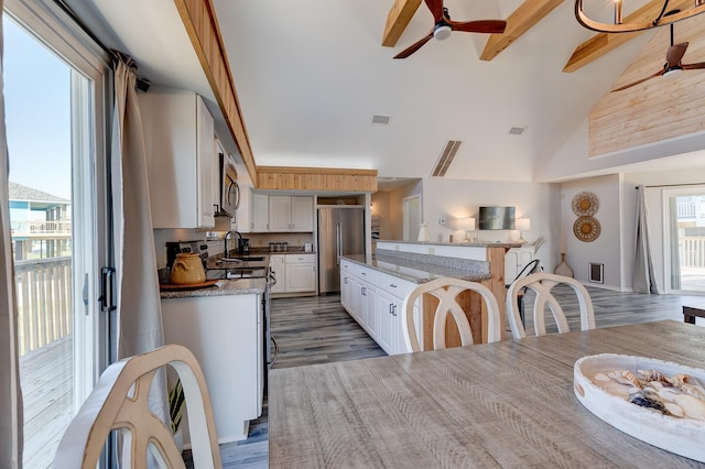 2332 Martinique, Crystal Beach, TX 77650 - kitchen with stainless steel appliances, a ceiling fan, white cabinets, wood finished floors, and high vaulted ceiling