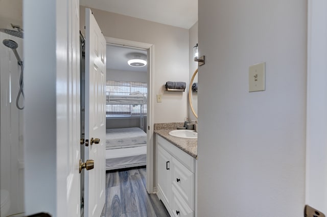 ensuite bathroom featuring vanity, ensuite bath, and wood finished floors