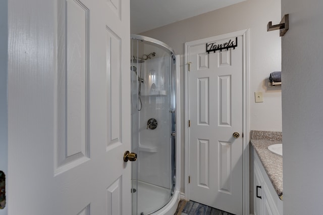 bathroom featuring vanity, hardwood / wood-style flooring, and a shower with shower door