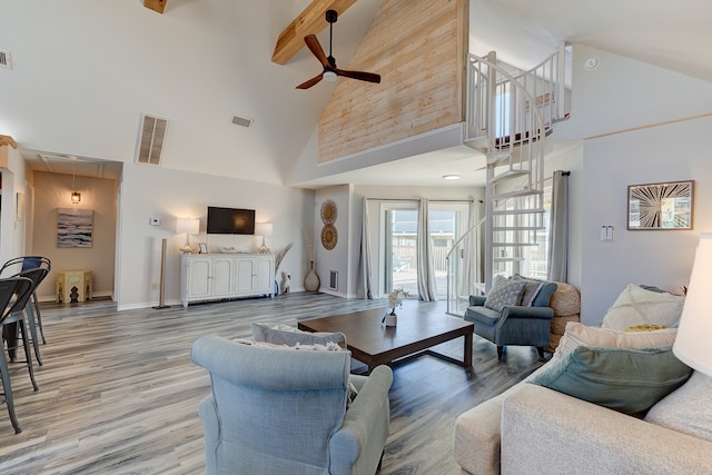 living area with light wood finished floors, attic access, visible vents, and beam ceiling