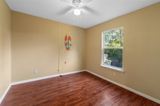 empty room featuring ceiling fan, dark wood-type flooring, and a textured ceiling