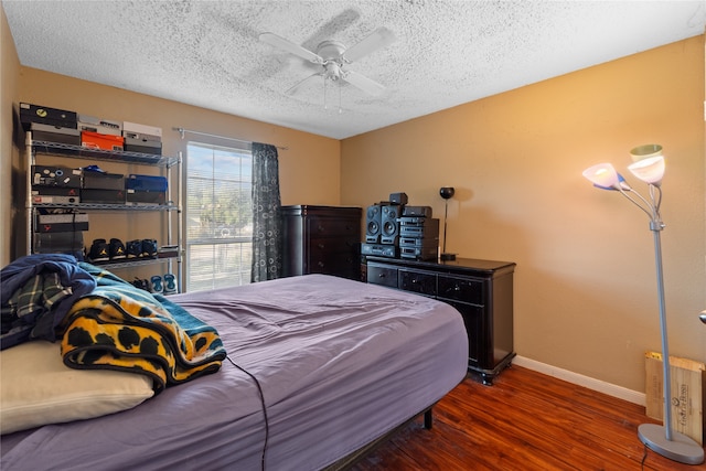 bedroom with a textured ceiling, ceiling fan, and dark hardwood / wood-style flooring