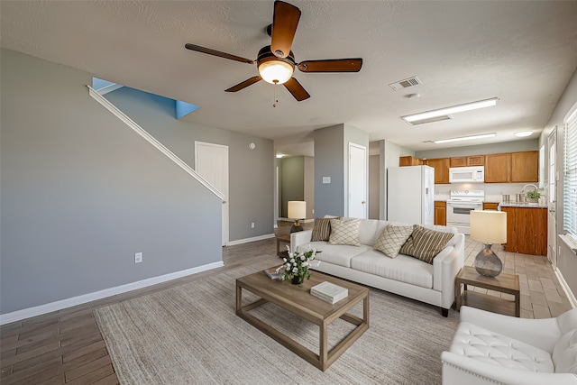 living room featuring ceiling fan, a textured ceiling, and light hardwood / wood-style flooring