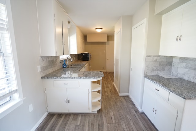 kitchen featuring light stone countertops, hardwood / wood-style floors, and white cabinetry