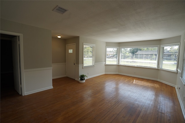 spare room with a textured ceiling, hardwood / wood-style floors, and a wealth of natural light