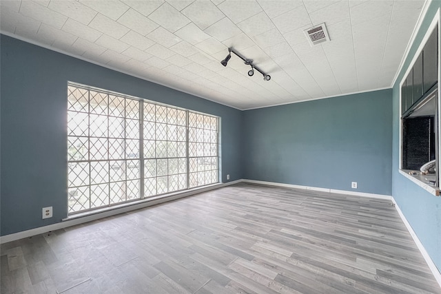 empty room with track lighting and hardwood / wood-style floors