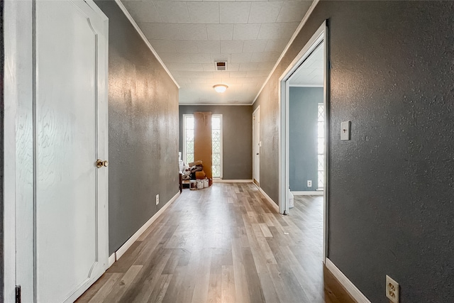 hallway featuring crown molding and light hardwood / wood-style flooring