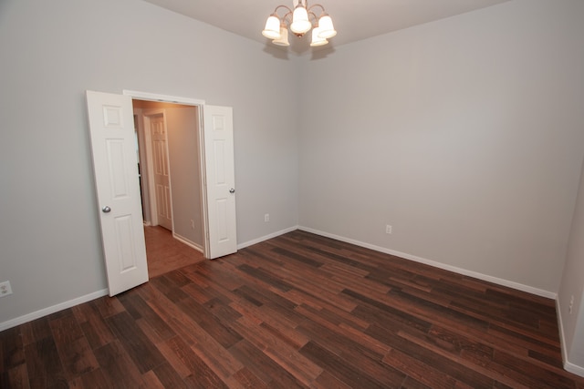 empty room with an inviting chandelier and dark hardwood / wood-style flooring