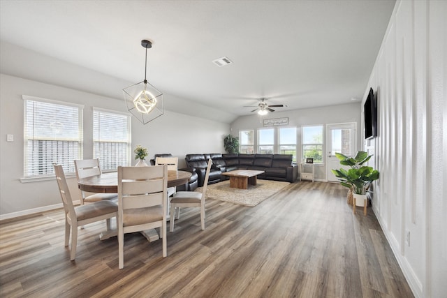 dining area with hardwood / wood-style flooring and ceiling fan with notable chandelier