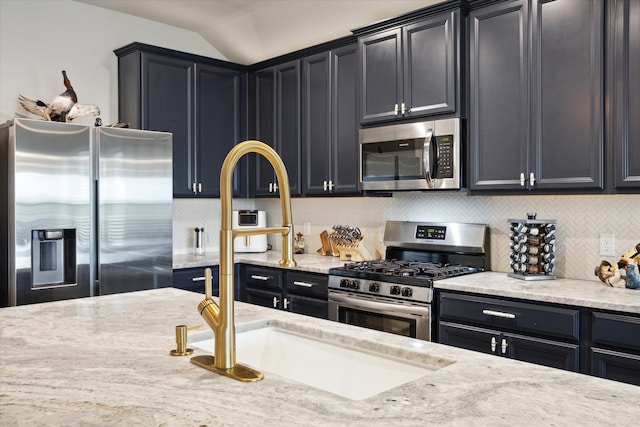 kitchen featuring tasteful backsplash, light stone counters, appliances with stainless steel finishes, vaulted ceiling, and sink