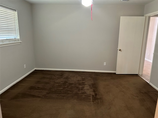 unfurnished room featuring dark carpet