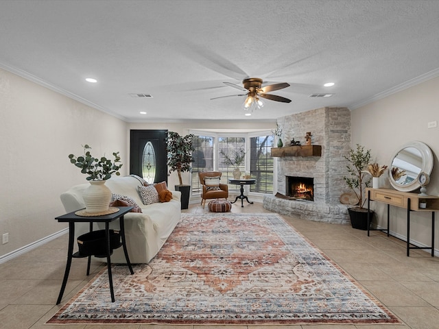 tiled living room featuring a stone fireplace, crown molding, ceiling fan, and a textured ceiling