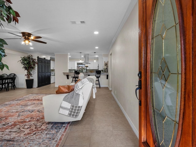 living room featuring ceiling fan, ornamental molding, and light tile patterned flooring